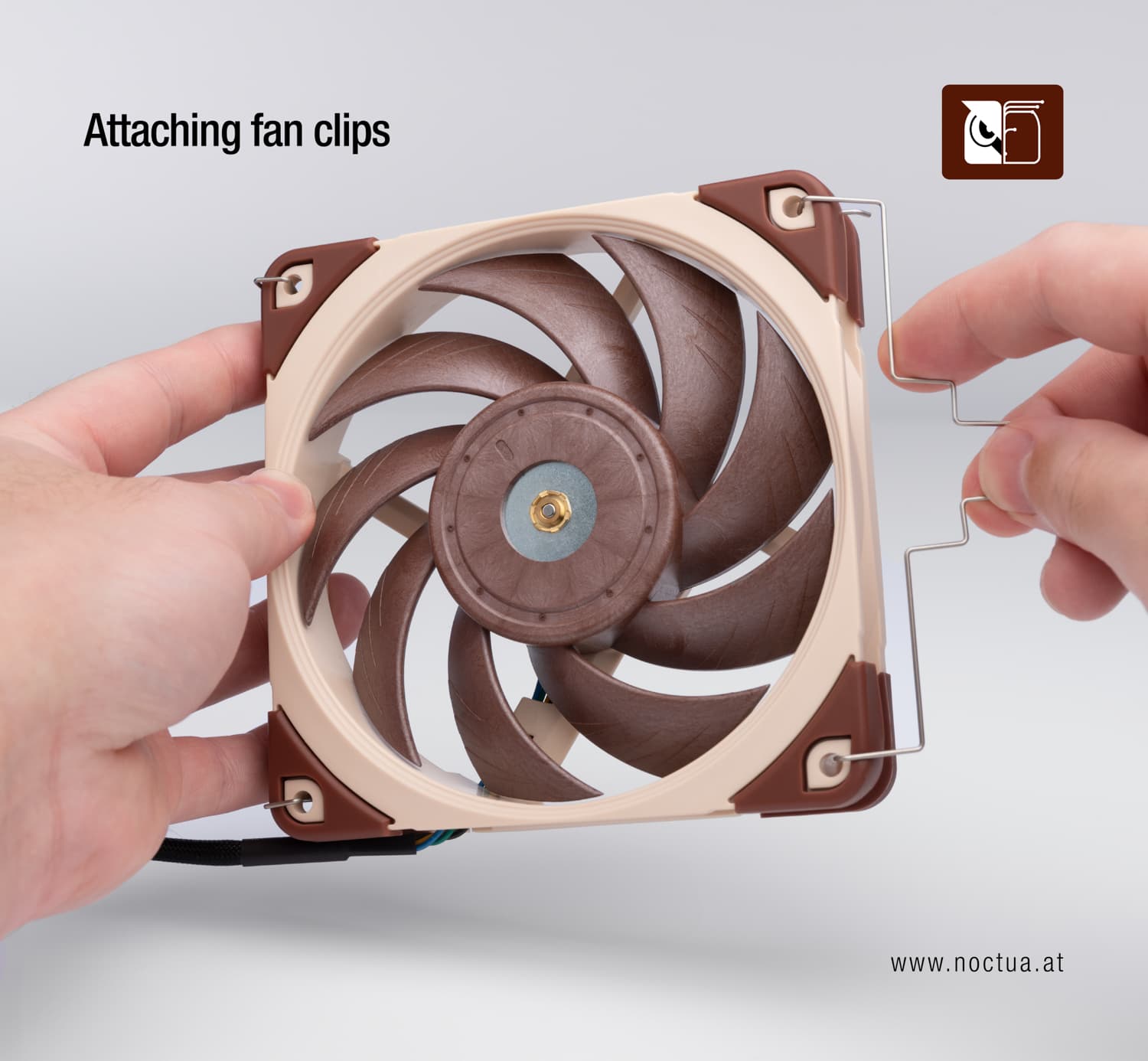 A fan is held in a hand, the other hand mounts a fan clip in two of the fans' mounting holes.