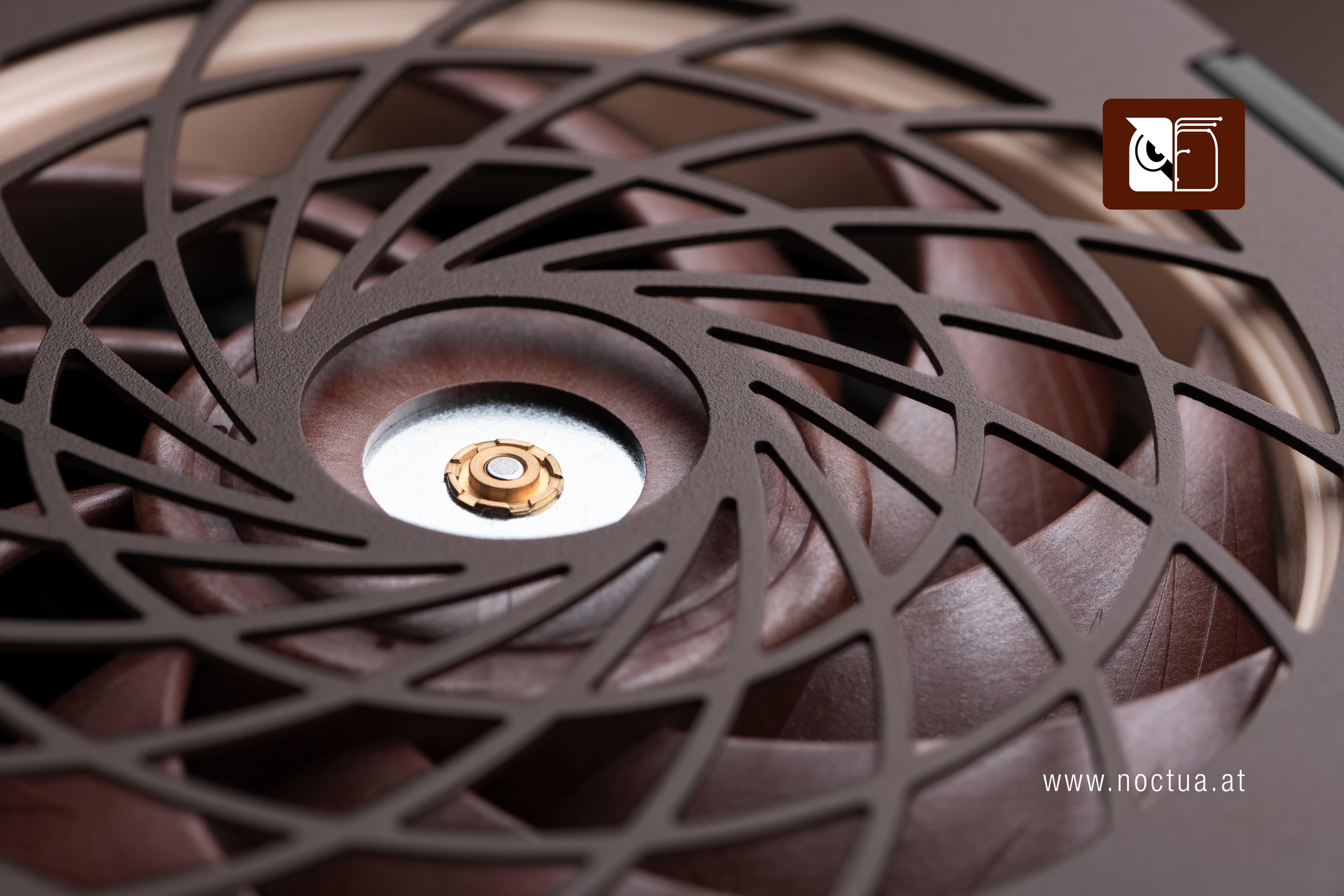 Close-up of an NF-A12x25 behind a spiral-patterned fan grill on a brown Seasonic PSU, the swept radial struts of the grill run perpendicular to the fan blades.